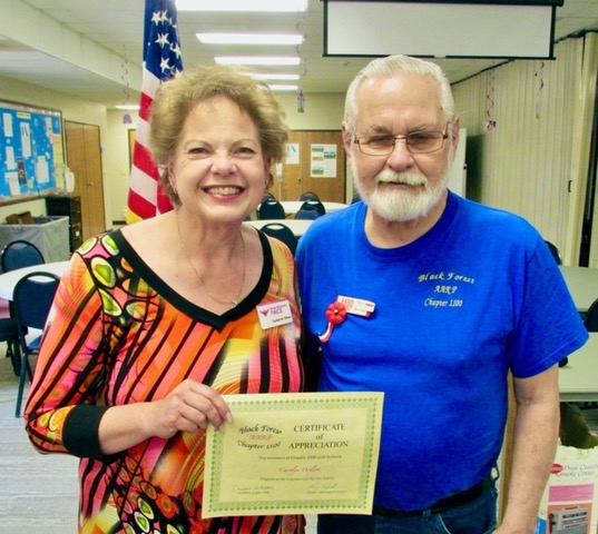 A man and woman standing next to each other holding a certificate.
