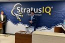 Two men standing in front of a sign that says stratus iq.