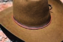A brown Beaver Fur cowboy hat sits on top of a log.
