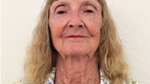 Jahna Badger in a floral shirt standing in front of a white wall.