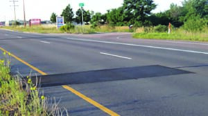 An image of a road with a black spot on it.