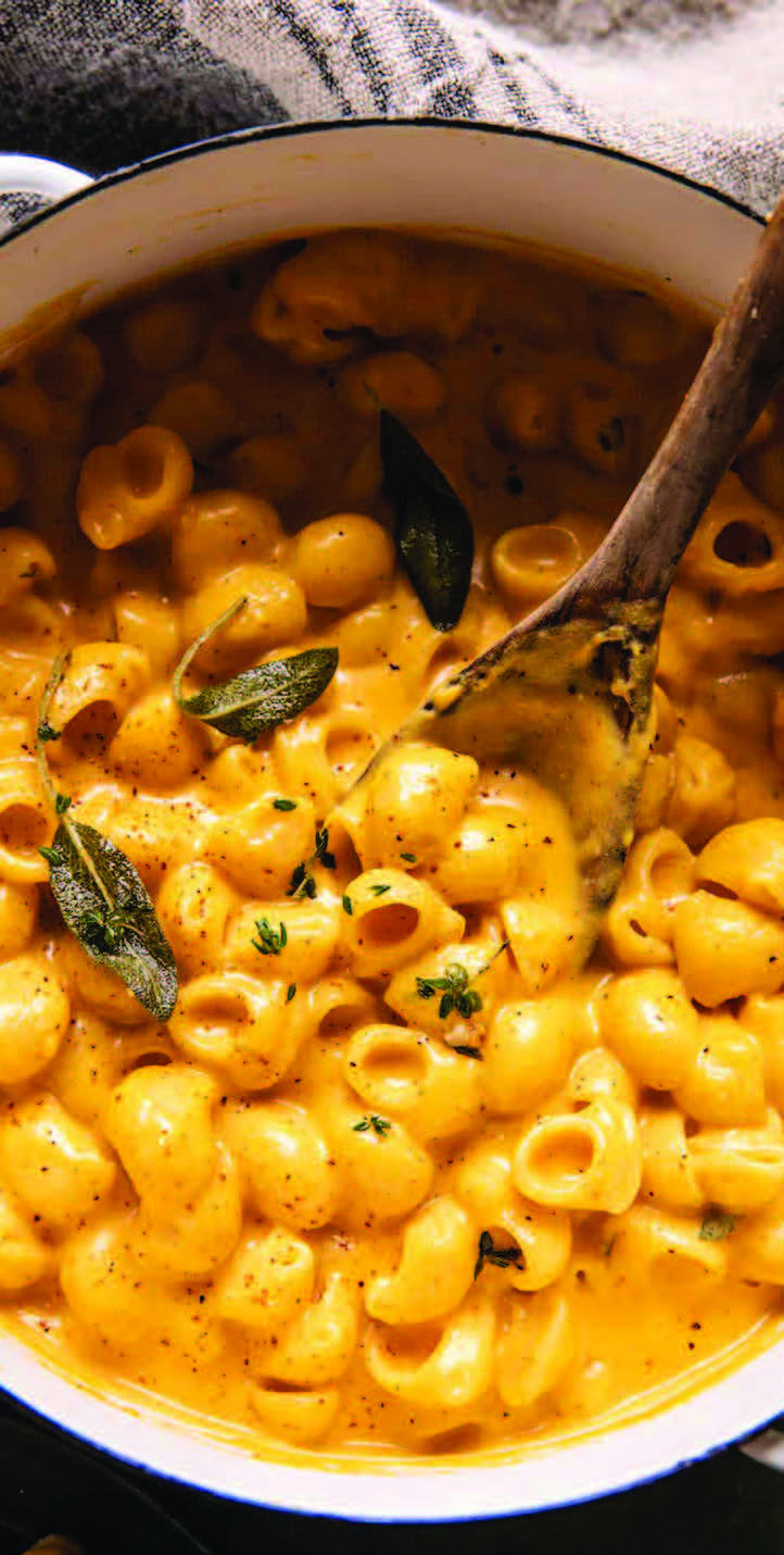 Macaroni and cheese in a pan with a wooden spoon.