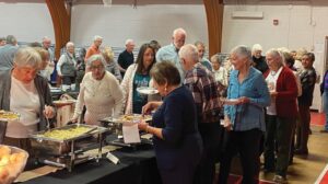 A group of people standing around a table with food