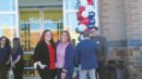 A group of people standing in front of a store with red, white and blue balloons