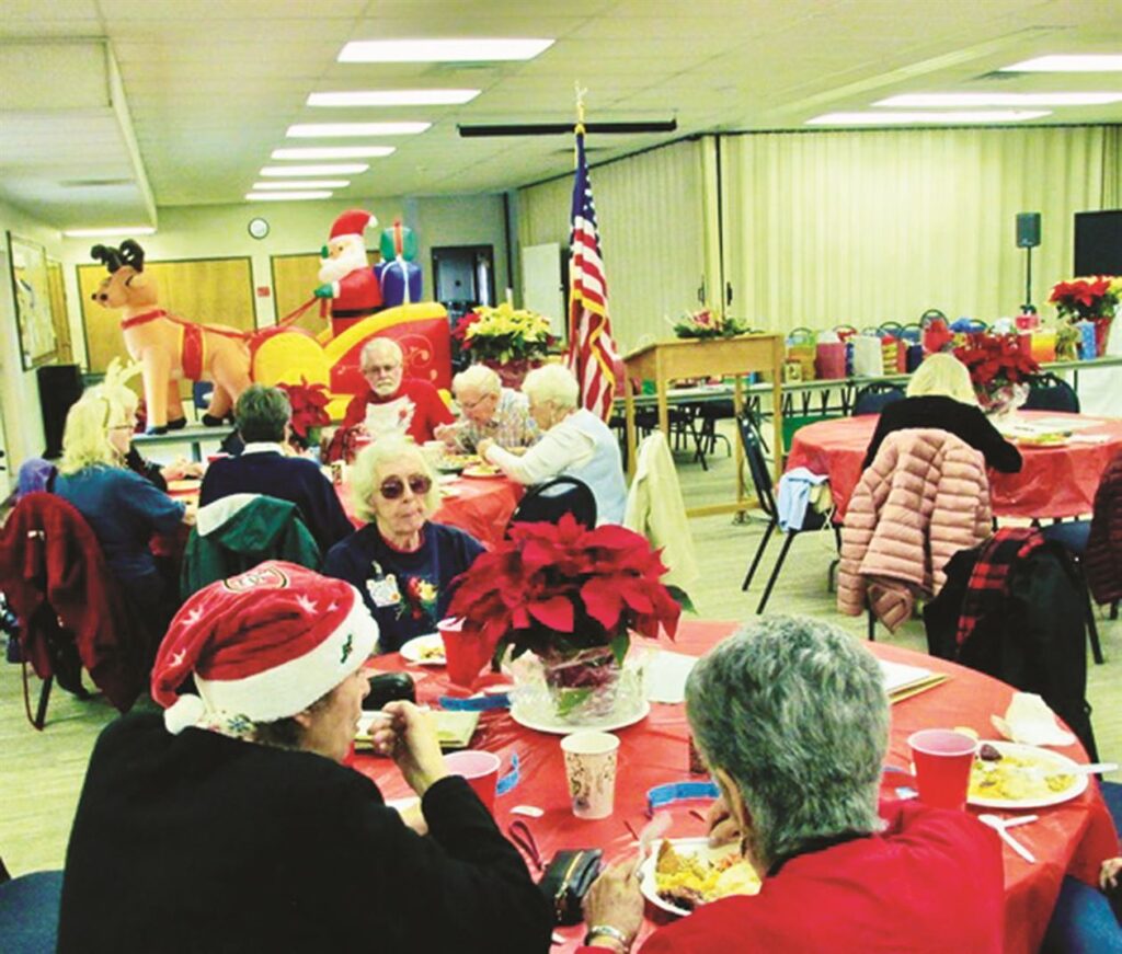 A group of people sitting at a table with santa hats on