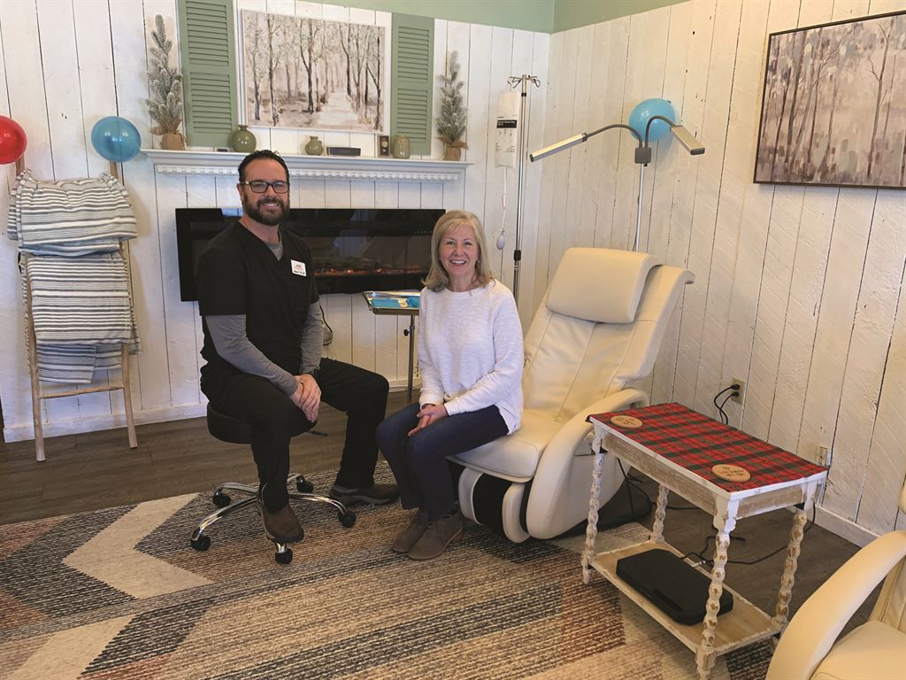 A man and woman sitting in a chair in a massage room