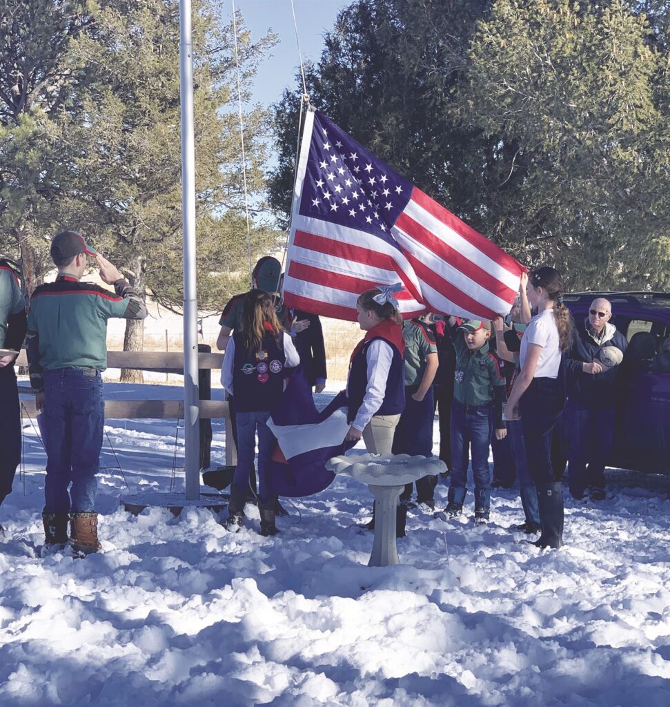 A group of people standing in the snow with an american flag
