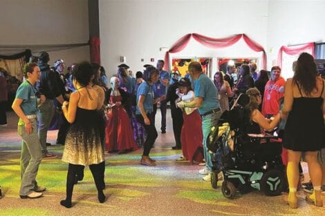 A group of people in various costumes at an indoor event with colorful lighting.