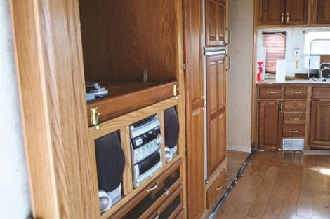 Interior view of an rv showing wooden cabinets and an entertainment system.