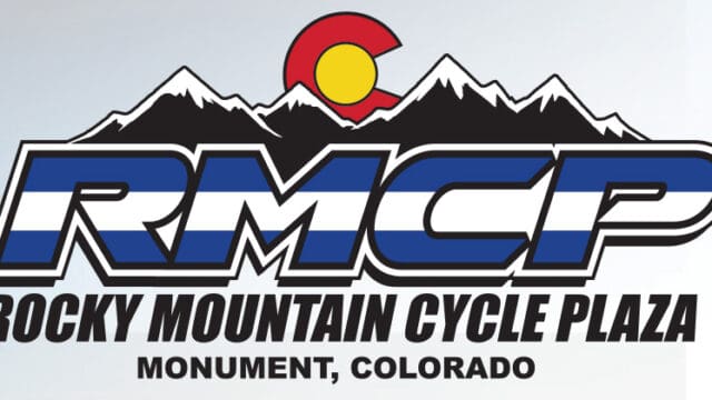 Logo of rocky mountain cycle plaza featuring a graphic representation of mountains and the colorado state flag, with the location in monument, colorado.