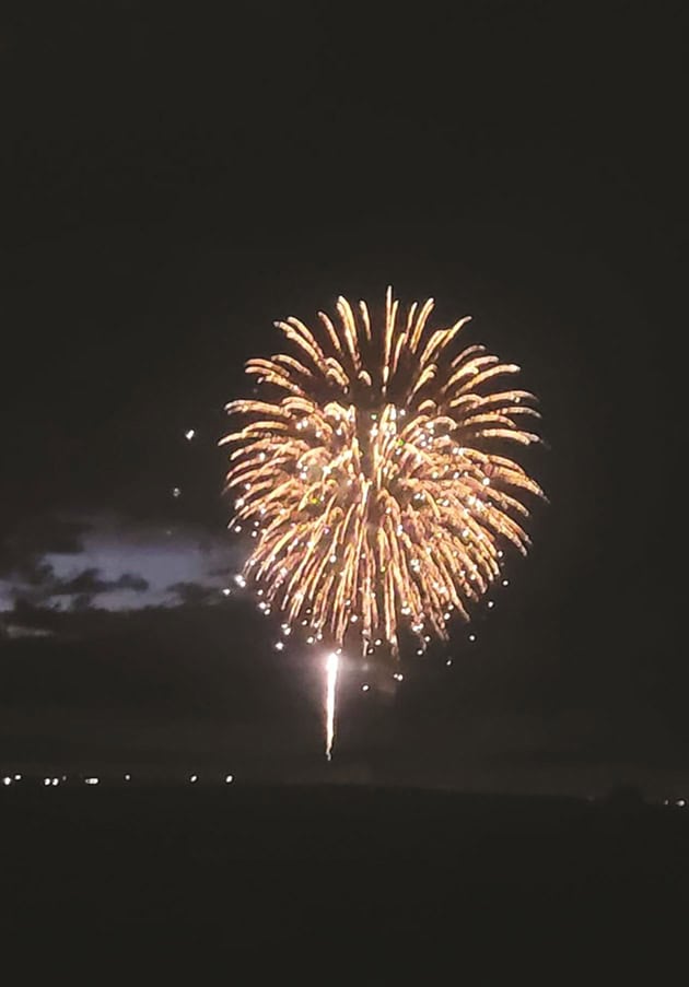 A burst of fireworks against a dark sky, with smaller fireworks spreading in circular patterns.