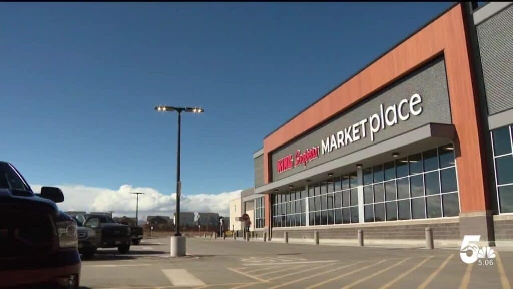 Exterior view of a King Soopers Marketplace store on a clear day, with a parking lot and a few parked cars in the foreground.