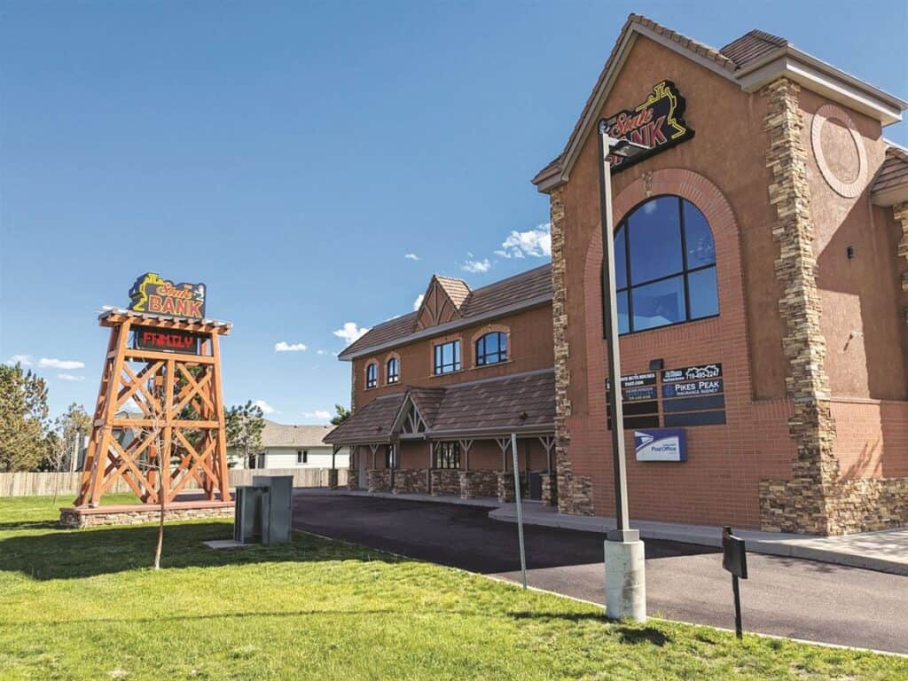 A two-story brick building with "Family Bank" signage and an adjacent decorative wooden structure also displaying "Family Bank." The building features a drive-through and a parking lot.