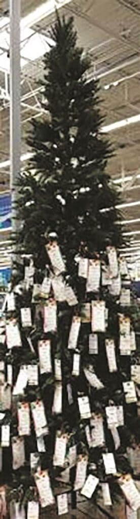 Tall Christmas tree with numerous price tags in a store setting.