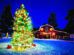 Festive Christmas tree with colorful lights and gifts in a snowy area near a red barn decorated with wreaths and lights, under a deep blue evening sky.