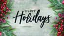 Festive greenery and red berries frame the words "Happy Holidays" on a wooden background.