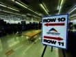 Job fair with booths set up in a large room. A sign points to Rows 10 and 11, labeled "Pikes Peak Workforce Center." People are visible in the background exploring the event.