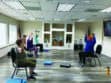 Three people are seated on chairs in a room, lifting weights as part of an exercise session.