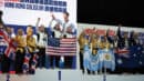 Group of medalists on a podium at a martial arts tournament. They are holding flags and plush toys, celebrating their victories.