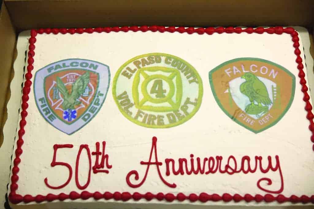 Rectangular cake with three fire department logos and "50th Anniversary" written in red icing.