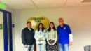 Four people stand indoors in front of a Colorado State University Extension sign, posing for a group photo.