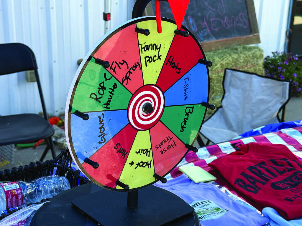 A colorful prize wheel with various handwritten options including "Rock," "Fly," "Hot," and "Fanny Pack," displayed on a table with assorted items.
