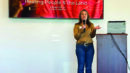 A woman stands at a podium, speaking in front of a screen displaying the presentation title "Advancing Food is Medicine: Healing People & the Land" at a FreshRx Oklahoma event.